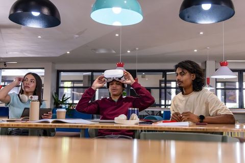 Young coworkers testing vr headset in modern coworking space for team innovation