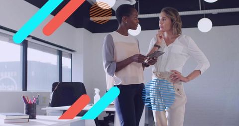 Two professional women collaborating over tablet in modern office with colorful graphic overlays