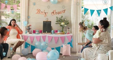 Smiling pregnant woman holding bump at pastel baby shower with balloons and bunting