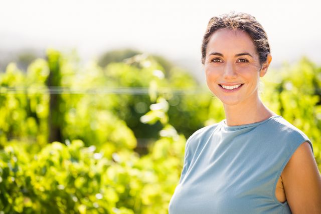 Portrait of smiling young woman at vineyard on sunny day