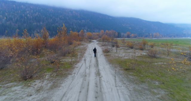 Solitary Figure Walking on Dirt Path in Countryside Autumn Landscape - Download Free Stock Images Pikwizard.com