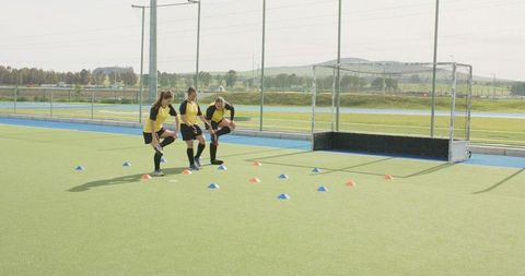 Diverse Female Soccer Team Stretching on Turf During Practice