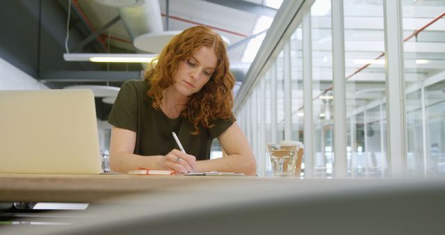 Focused Businesswoman Writing in Modern Office Environment - Download Free Stock Images Pikwizard.com