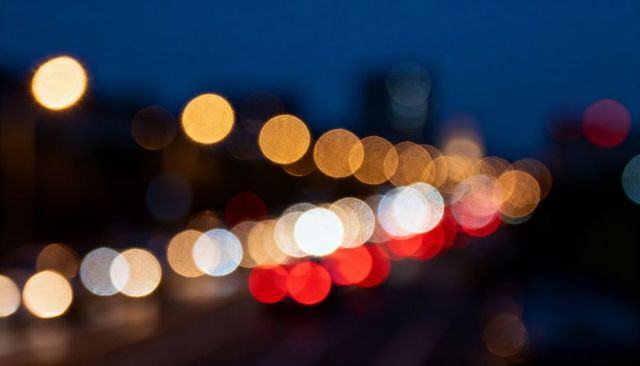 Glowing traffic lights blurring into colorful night bokeh with headlights taillights