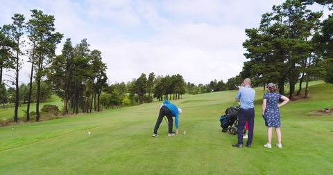 Group of Golfers in Action on Green Fairway Under Clear Sky