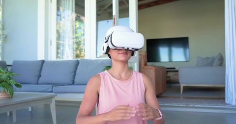 African woman wearing VR headset and smartwatch exploring virtual reality in home lounge