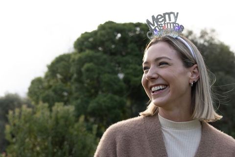 Smiling woman wearing merry christmas headband and cozy cardigan outdoor portrait
