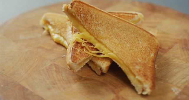Grilled cheese sandwich with golden brown toast and melted cheese is placed on a wooden board. Ideal for recipes, food blogs, comfort food promotions, and lunch menu ideas.