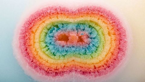 Vibrant rainbow geode cross section showing concentric crystalline rings and textures