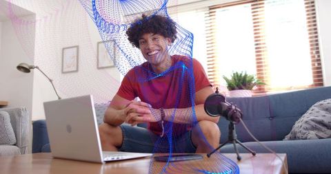 Smiling creator streaming from living room with laptop, microphone and ar overlay