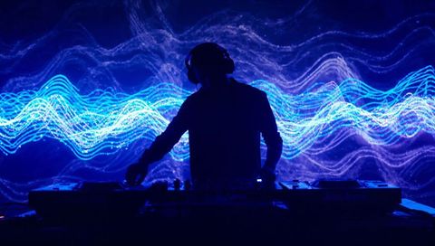 Mixing DJ Silhouette Performing Behind Neon Waveform Visuals with Headphones and Mixer