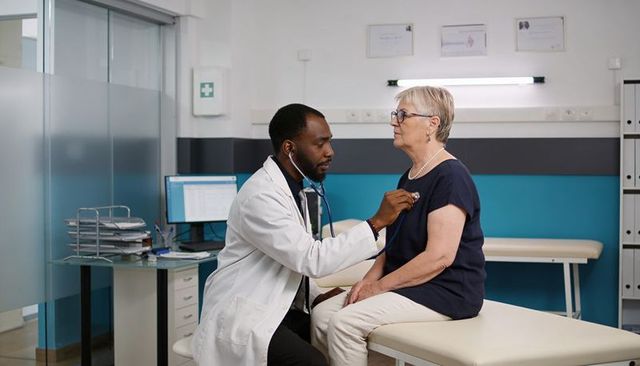 Doctor listening and examining senior patient with stethoscope in modern medical clinic