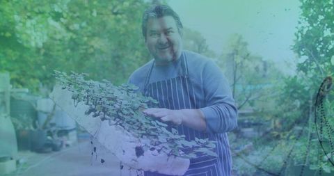 Senior Gardener Holding Seedling Tray in Lush Backyard Nursery