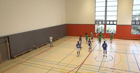 Teen athlete dunking basketball on indoor court