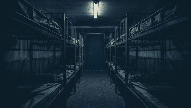 Dimly Lit Room with Metal Bunk Beds and Fluorescent Lighting