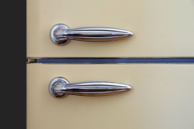 Close-up view of chrome door handles on retro-style refrigerator, perfect for showcasing vintage kitchen appliances, retro home decor, or mid-century modern lifestyle. Useful for blogs, catalogs, and design inspiration in interior design and kitchen remodeling.