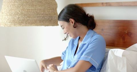 Relaxed Woman Using Laptop in Cozy Bedroom Setting
