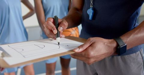 Coach Creating Basketball Strategy on Court with Team