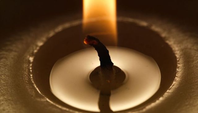 Charred Candle Wick Glowing Over Molten Wax Pool Macro Closeup Warm Ember Reflection