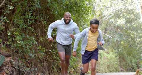 African american father and son running on sunlit trail enjoying family fitness outdoors