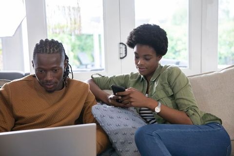 Couple Relaxing on Sofa with Laptop and Smartphone