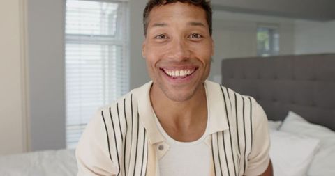 Relaxed man smiling in cozy bedroom setting
