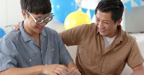 Asian Father and Son Celebrating With a Gift Exchange at Home