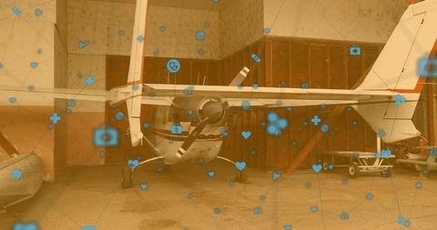 Small propeller airplane in hangar with digital icons overlay