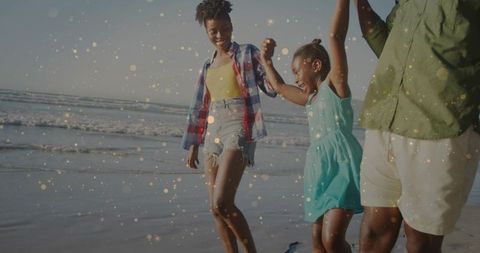 Family walking hand-in-hand on beach at golden hour with sparkling bokeh and laughter