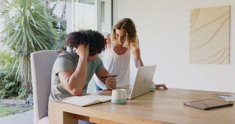 Young Couple Collaborating on a Project at Home Using Laptop