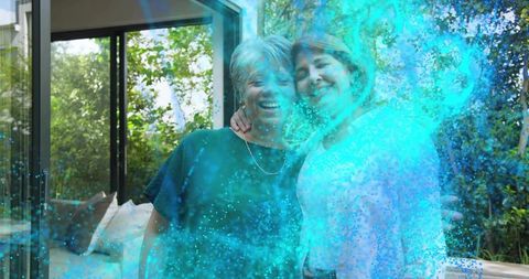 Smiling mature women embracing on patio with turquoise light overlay and garden backdrop