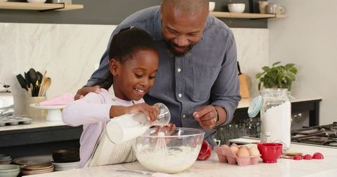 African American Father and Daughter Baking Together in Modern Kitchen