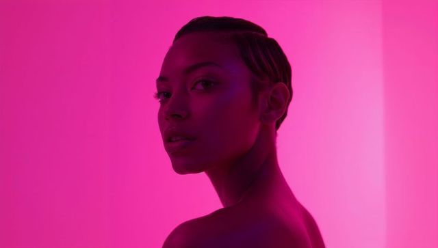 Glamorous model in vibrant pink lighting with bare shoulders