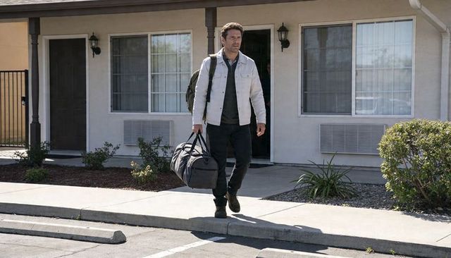 Walking traveler carrying duffel and backpack outside motel, middle-aged man departing