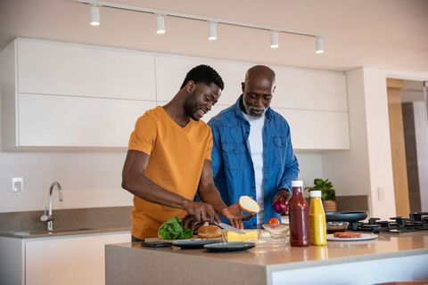 Happy father and son preparing lunch together in modern kitchen