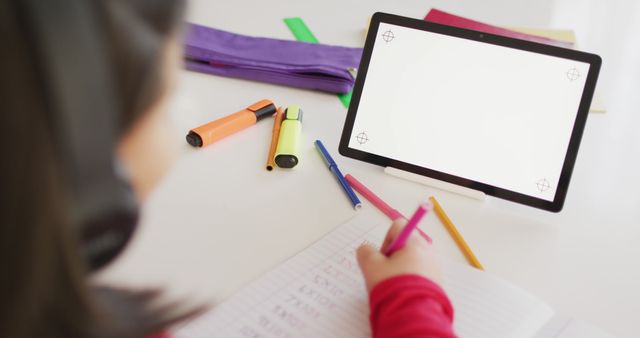 Child studying at home, using tablet and writing in notebook. Ideal for educational articles, online learning materials, illustrations of home study environments, and technology in education.