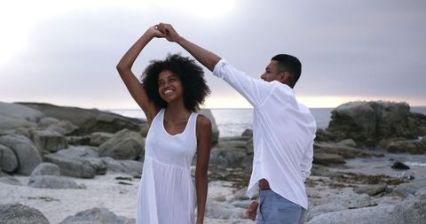 Romantic Couple Dancing on Rocky Beach at Sunset