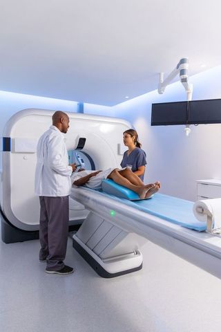 African american radiology team positioning patient for ct scan in modern imaging suite