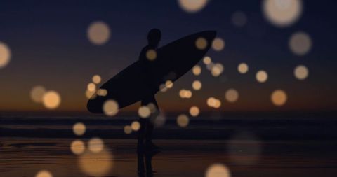 Silhouette of Surfer at Dusk with Captivating Bokeh Lights