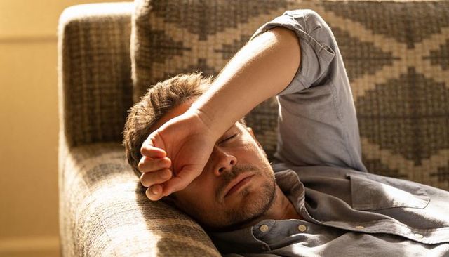 Man resting on sunlit zigzag sofa relaxing on patterned couch in cozy living room