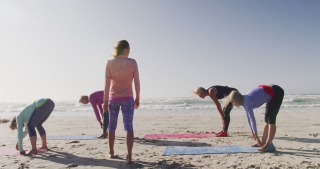 Group of seniors practicing yoga on a seaside beach at sunset. Perfect for use in wellness articles, fitness blogs, senior health features, and lifestyle promotions emphasizing outdoor activities and physical wellness.