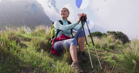 Mature Woman Hiking on Mountainside with Trekking Poles and Backpack
