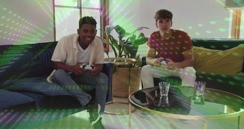Friends playing video games on navy sofa with white controllers in modern living room