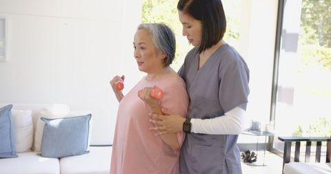 Senior Woman Exercising with Dumbbells at Home with Physical Therapist