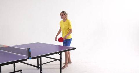 Focused woman playing table tennis indoors in casual sportswear