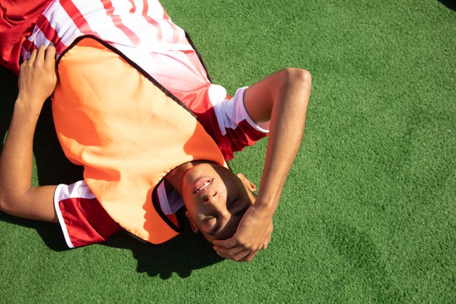 Biracial male field hockey player, practicing before a game, lying on a pitch frustrated. Sport game competition.
