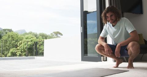 Man Preparing for Home Workout with Yoga Mat, Bright Sunlit Patio View - Download Free Stock Images Pikwizard.com