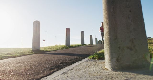 Sunny Urban Landscape with Jogging Person on Paved Path - Download Free Stock Images Pikwizard.com