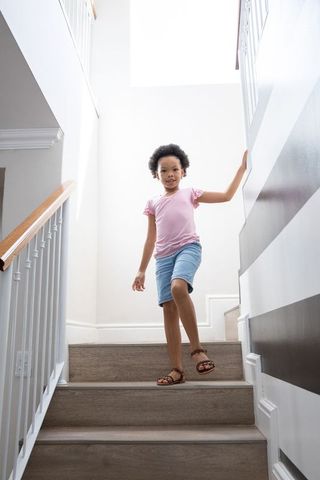Young Girl Descending Staircase in Bright Home Interior