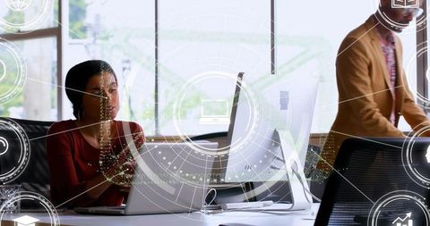 Professional woman reviewing laptop with digital hud overlay in modern coworking office
